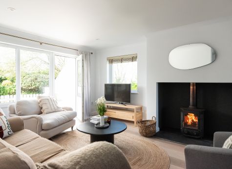 Bright, comfy sitting room with log burner and doors leading to patio.